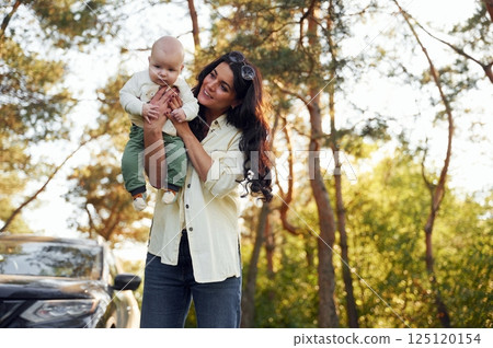Baby is on the hands. Beautiful mother with her little son is outdoors in the forest 125120154