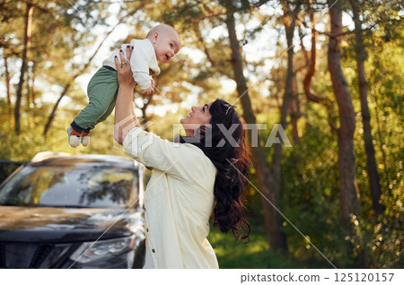 Beautiful mother with her little son is outdoors in the forest Beautiful mother with her little son is outdoors in the forest 125120157