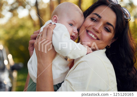 Holding her baby in hands. Beautiful mother with her little son is outdoors in the forest 125120165