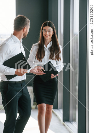 Holding tablet. Man and woman in formal clothes are working together indoors Holding tablet. Man and woman in formal clothes are working together indoors 125120263