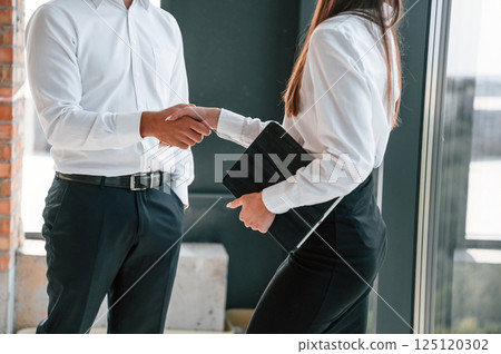 Making a deal, handshake. Industry workers are in the building at daytime. Construction location Making a deal, handshake. Industry workers are in the building at daytime. Construction location 125120302
