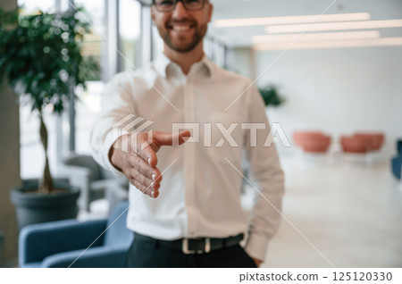 Giving hand to make handshake. Elegant man in formal clothes is indoors Giving hand to make handshake. Elegant man in formal clothes is indoors 125120330