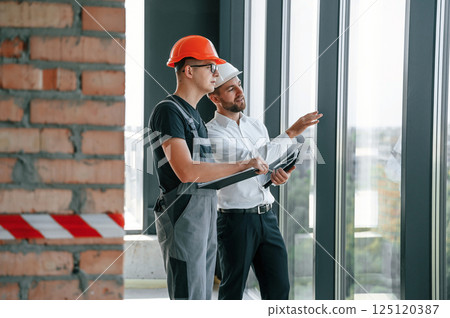Manager with foreman are working on the construction site together 125120387