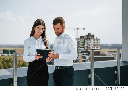 Cloudy sky. Man with woman are working on the construction project together outside Cloudy sky. Man with woman are working on the construction project together outside 125120411