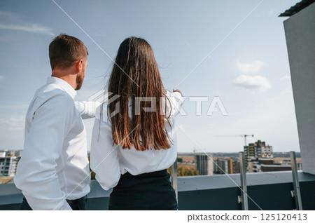 Cloudy sky. Man with woman are working on the construction project together outside Cloudy sky. Man with woman are working on the construction project together outside 125120413