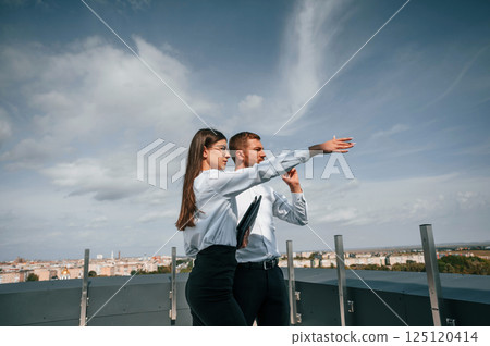 Cloudy sky. Man with woman are working on the construction project together outside Cloudy sky. Man with woman are working on the construction project together outside 125120414