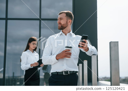 Holding drink and notepad. Man with woman are working on the construction project together outside 125120421