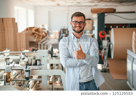 Handsome man is standing and smiling. Print house worker in white clothes is indoors Handsome man is standing and smiling. Print house worker in white clothes is indoors 125120583