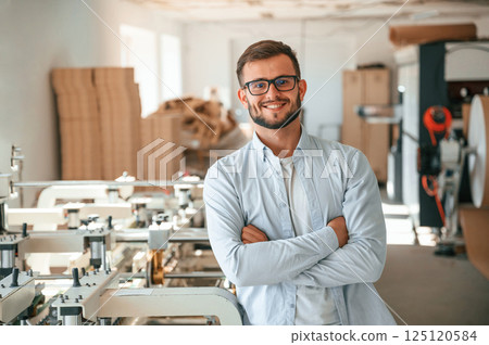 Handsome man is standing and smiling. Print house worker in white clothes is indoors Handsome man is standing and smiling. Print house worker in white clothes is indoors 125120584