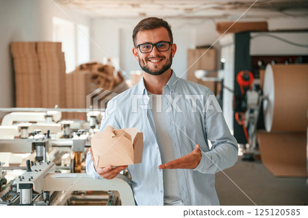 Holding and showing wooden sheets. Print house worker in white clothes is indoors Holding and showing wooden sheets. Print house worker in white clothes is indoors 125120585