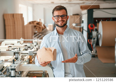 Holding and showing wooden sheets. Print house worker in white clothes is indoors Holding and showing wooden sheets. Print house worker in white clothes is indoors 125120586
