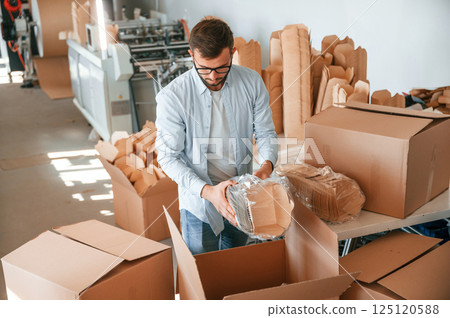 Packaging the wooden sheets. Print house worker in white clothes is indoors Packaging the wooden sheets. Print house worker in white clothes is indoors 125120588