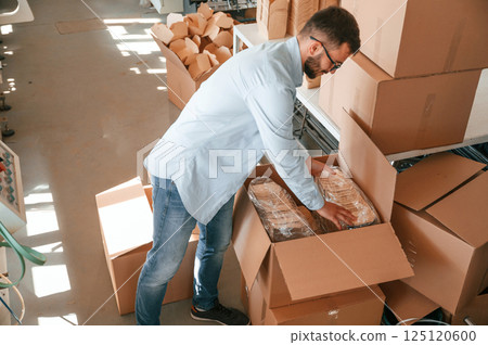 Packaging the wooden sheets. Print house worker in white clothes is indoors Packaging the wooden sheets. Print house worker in white clothes is indoors 125120600