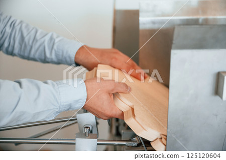 Operating printing cutting machine. Print house worker in white clothes is indoors Operating printing cutting machine. Print house worker in white clothes is indoors 125120604