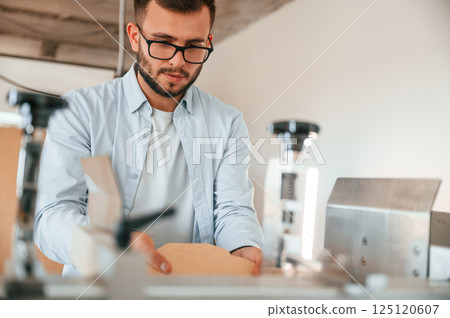 Using the cutting machine. Print house worker in white clothes is indoors 125120607