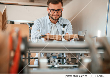 Using the cutting machine. Print house worker in white clothes is indoors Using the cutting machine. Print house worker in white clothes is indoors 125120609