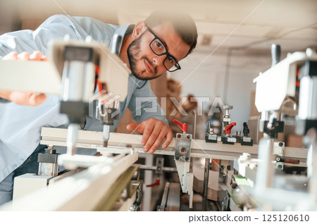 Using the cutting machine. Print house worker in white clothes is indoors 125120610