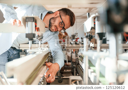 Process of using the cutting machine. Print house worker in white clothes is indoors Process of using the cutting machine. Print house worker in white clothes is indoors 125120612