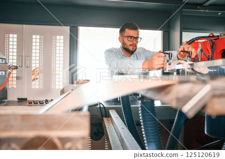 Sheet cutting machine. Operating device. Print house worker in white clothes is indoors Sheet cutting machine. Operating device. Print house worker in white clothes is indoors 125120619
