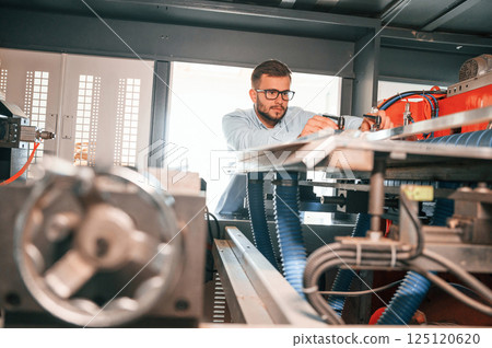 Sheet cutting machine. Operating device. Print house worker in white clothes is indoors Sheet cutting machine. Operating device. Print house worker in white clothes is indoors 125120620