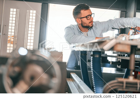 Sheet cutting machine. Operating device. Print house worker in white clothes is indoors Sheet cutting machine. Operating device. Print house worker in white clothes is indoors 125120621