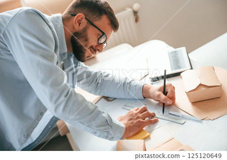 Drawing by the table. Print house worker in white clothes is indoors Drawing by the table. Print house worker in white clothes is indoors 125120649