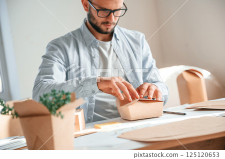 Process of making beautiful little wooden box. Print house worker in white clothes is indoors Process of making beautiful little wooden box. Print house worker in white clothes is indoors 125120653