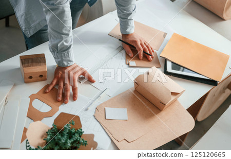 Standing by the table and looking at draws. Print house worker in white clothes is indoors Standing by the table and looking at draws. Print house worker in white clothes is indoors 125120665