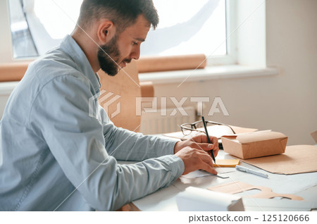 Using pen to draw some new design. Print house worker in white clothes is indoors 125120666