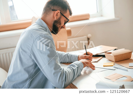 Using pen to draw some new design. Print house worker in white clothes is indoors Using pen to draw some new design. Print house worker in white clothes is indoors 125120667