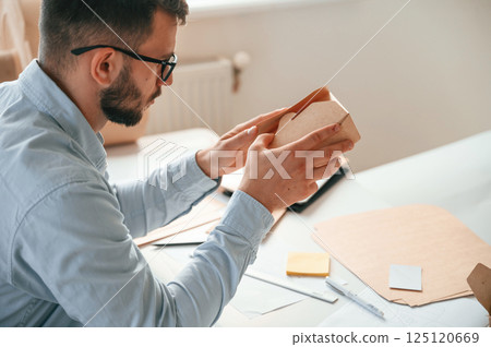 Holding little wooden box. Print house worker in white clothes is indoors Holding little wooden box. Print house worker in white clothes is indoors 125120669