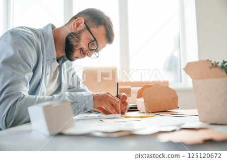 Using pen to draw some new design. Print house worker in white clothes is indoors Using pen to draw some new design. Print house worker in white clothes is indoors 125120672