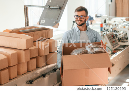 Holding the box. Print house worker in white clothes is indoors Holding the box. Print house worker in white clothes is indoors 125120693