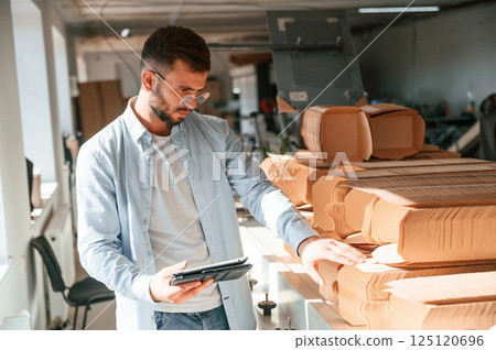 With notepad in hand. Print house worker in white clothes is indoors With notepad in hand. Print house worker in white clothes is indoors 125120696