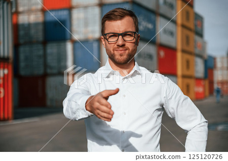 Making a deal, giving hand. Male worker is on the location with containers Making a deal, giving hand. Male worker is on the location with containers 125120726