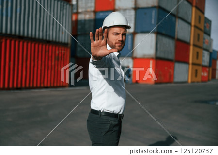 Stop, gesture. By the hand. Male worker is on the location with containers 125120737