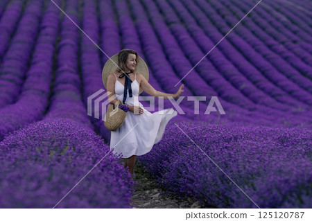 A woman is standing in a field of purple flowers A woman is standing in a field of purple flowers 125120787