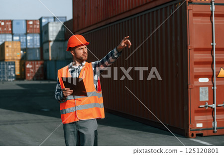 Giving instructions by the hand. Male worker is on the location with containers Giving instructions by the hand. Male worker is on the location with containers 125120801