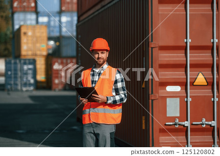 With tablet in hands. Male worker is on the location with containers With tablet in hands. Male worker is on the location with containers 125120802