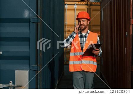Using phone and holding tablet. Male worker is on the location with containers Using phone and holding tablet. Male worker is on the location with containers 125120804