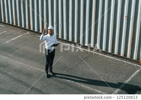 Top view. With tablet. Male worker is on the location with containers 125120813