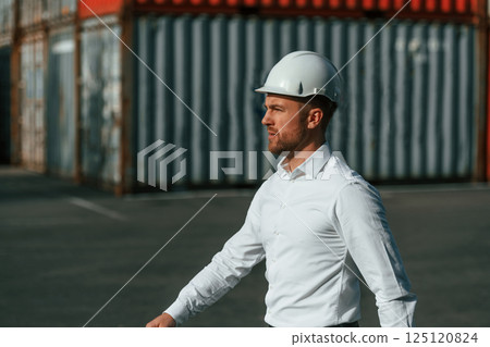 Walking, side view. Male worker is on the location with containers 125120824