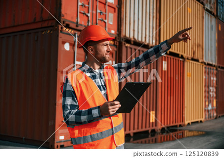 Digital tablet in hands. Male worker is on the location with containers 125120839
