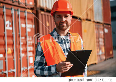 Standing with tablet in hands. Male worker is on the location with containers Standing with tablet in hands. Male worker is on the location with containers 125120840