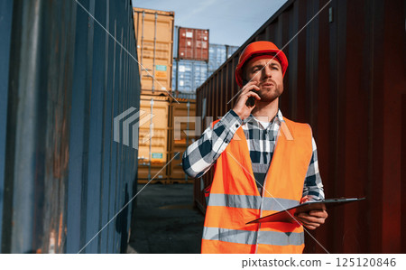 Having conversation by phone. Male worker is on the location with containers Having conversation by phone. Male worker is on the location with containers 125120846