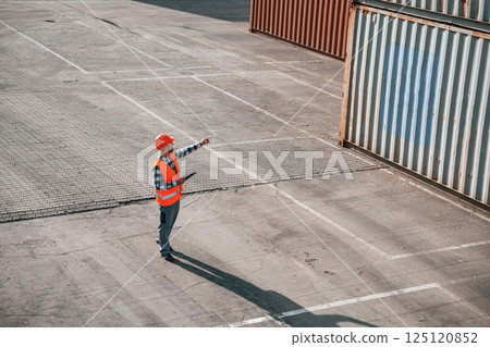 Conception of business. Walking with tablet. Male worker is on the location with containers Conception of business. Walking with tablet. Male worker is on the location with containers 125120852