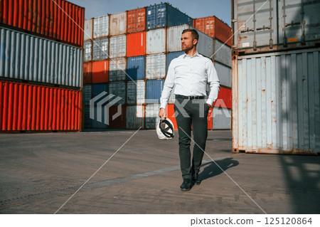 Front view. Male worker is on the location with containers Front view. Male worker is on the location with containers 125120864