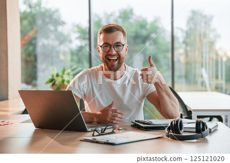 Sitting and smiling. Positive man in formal clothes is working in the modern office 125121020