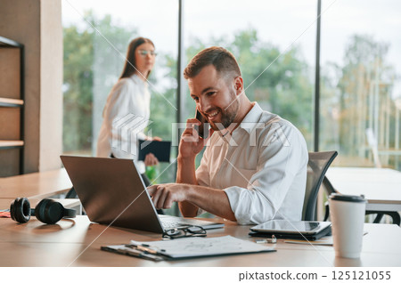 Successful deal. Using laptop. Man and woman are working in the modern office together Successful deal. Using laptop. Man and woman are working in the modern office together 125121055