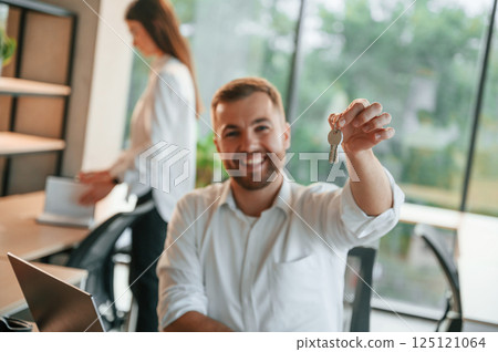 Holding keys for the new apartment. Man and woman are working in the modern office together 125121064